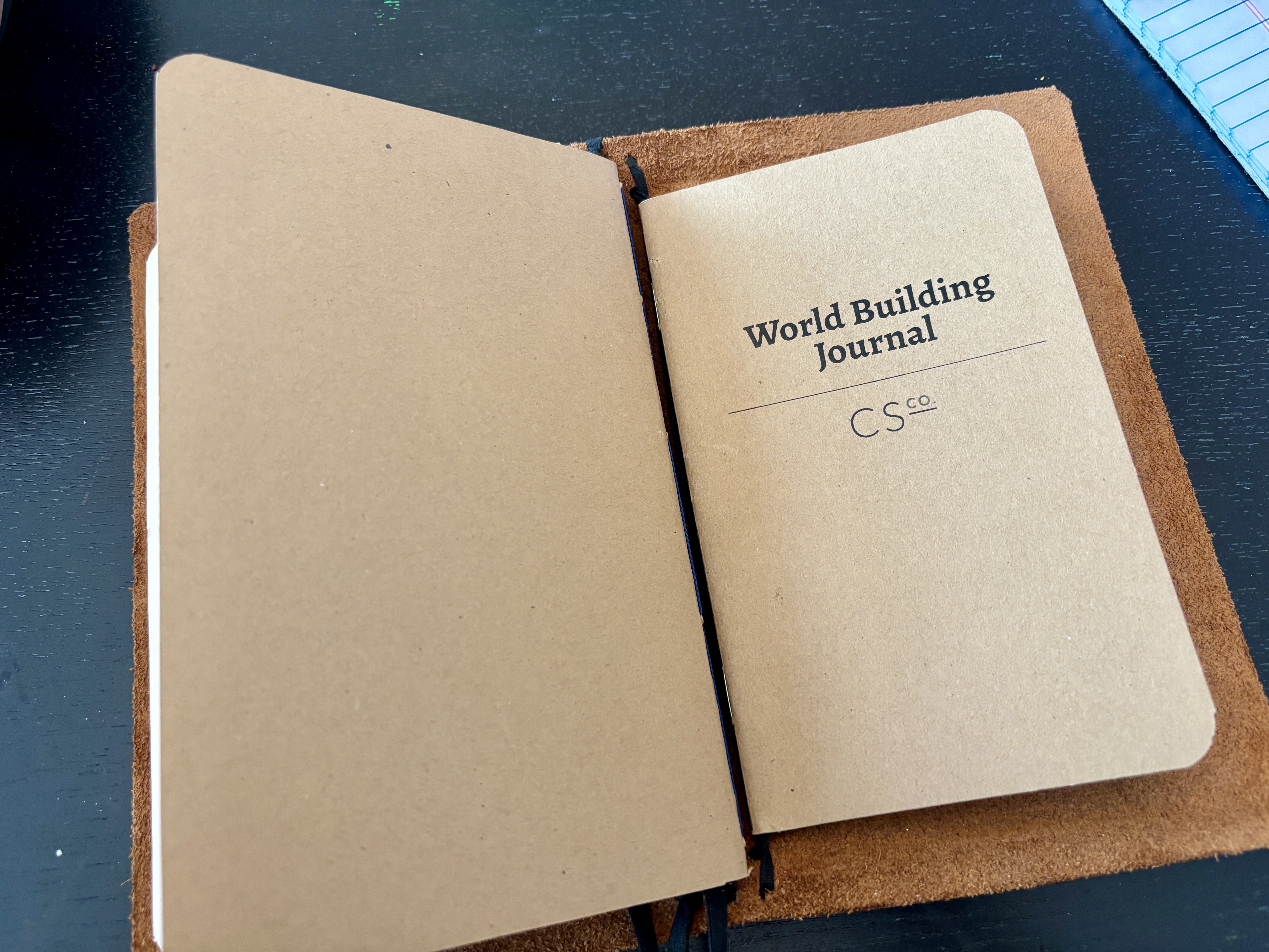 The notebook cover open to the "World Building Journal".